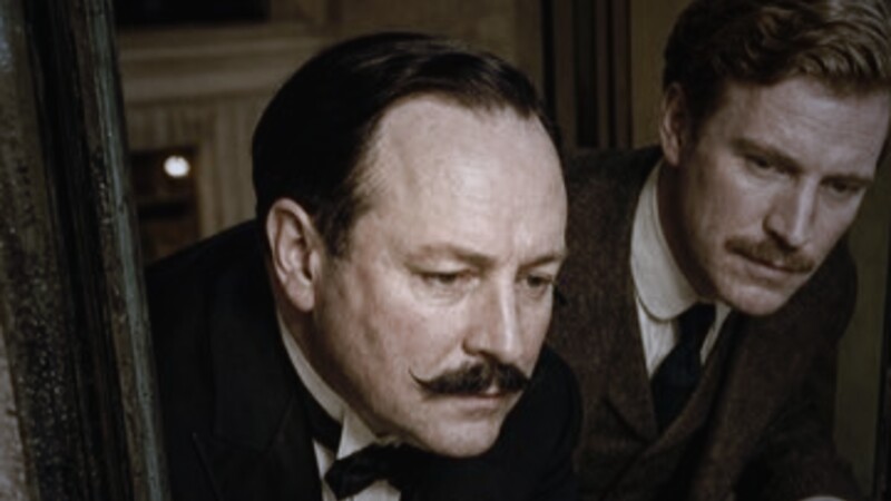 Hercule Poirot by lamplight, moustache and evening dress.